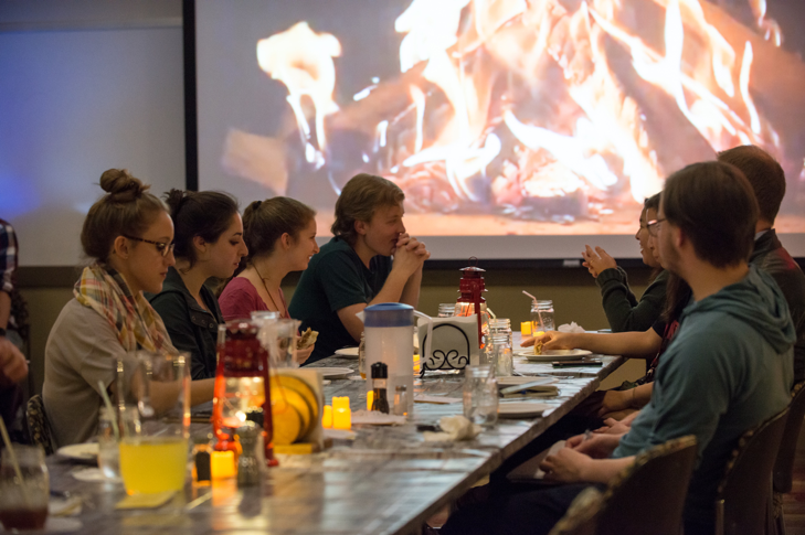 A close-up shot of the student participants sitting near the projected campfire as the main course winds down. 