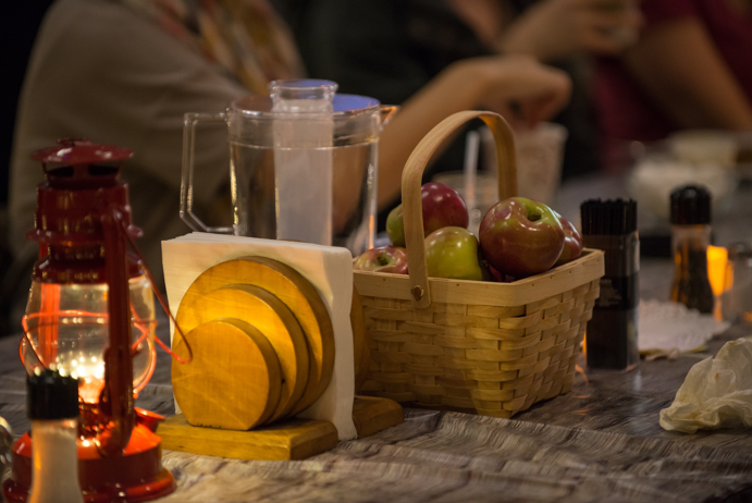 A close-up shot of the table decor during the dessert course, featuring the addition of a picnic basket full of fresh apples.